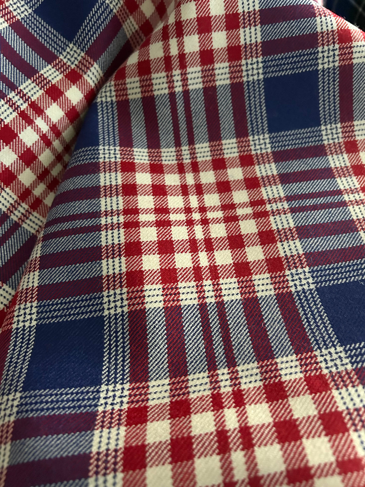 A close-up of USA tartan fabric with a tartan pattern in navy blue, red, and off-white.