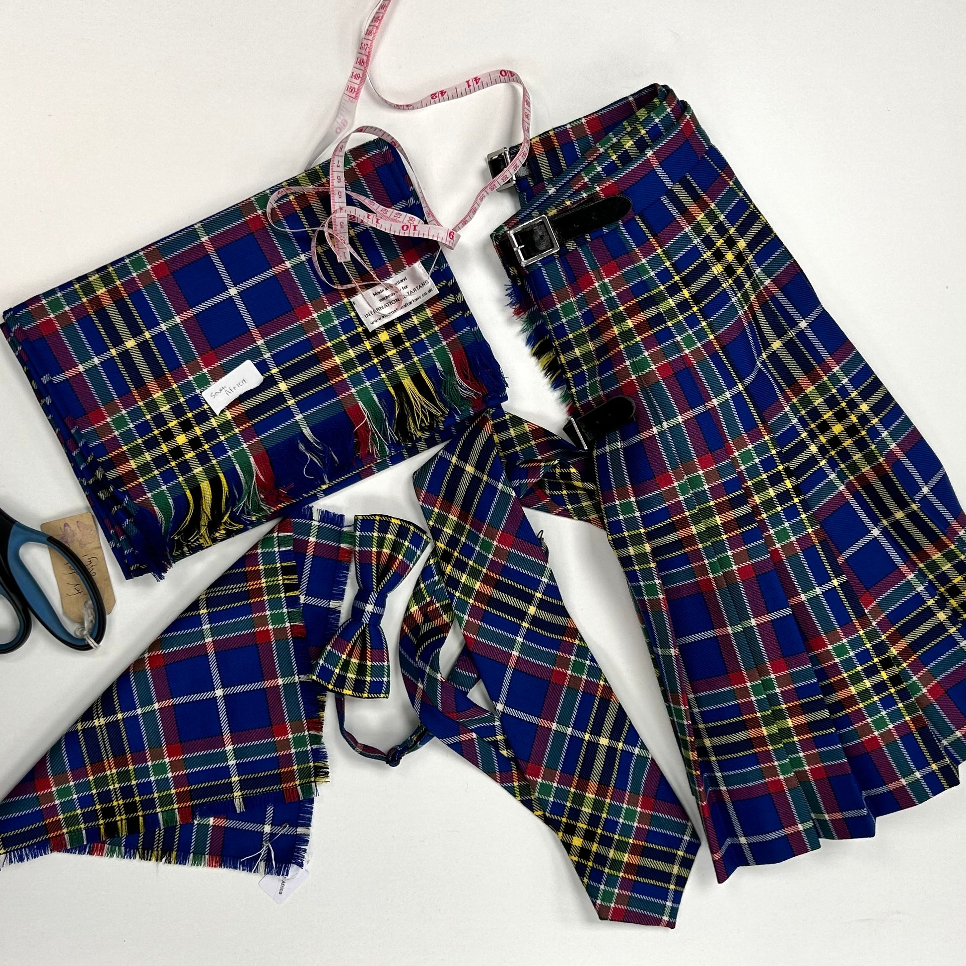 An arrangement of handmade South Africa tartan products - a ladies kilt, tie, bow-tie, scarf and pocket square.